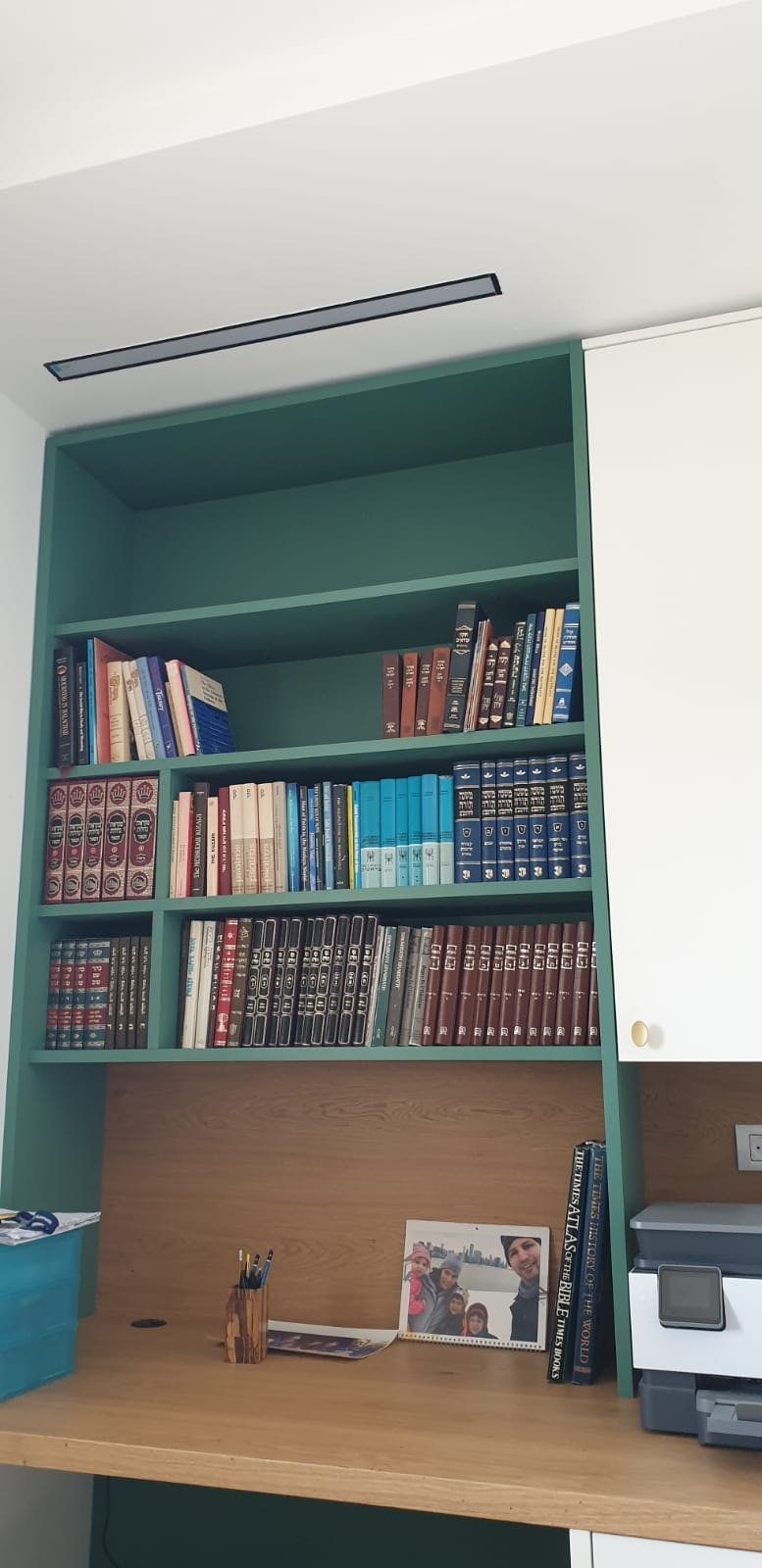שולחן כתיבה מתחת למדפים בגומחה הירוקה — ספריות, חדרי עבודה ויחידות אחסון בתכנון הילה עוז, מודיעין